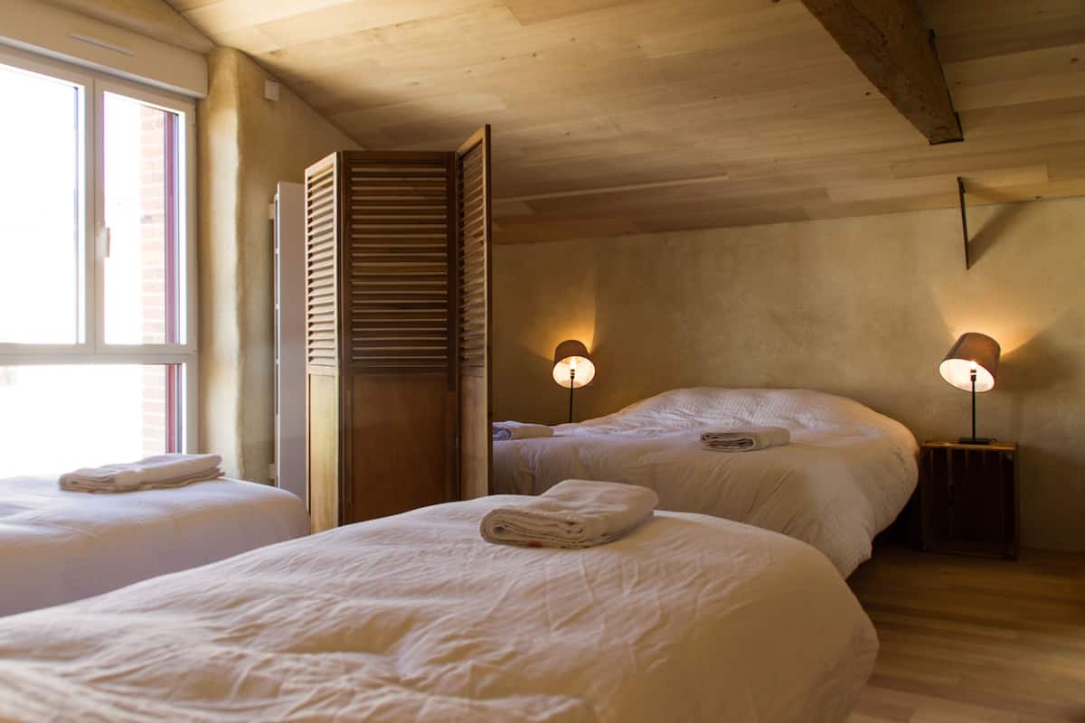 Une chambre d’hôtel avec deux lits, un plafond en bois et deux lampes de chevet.