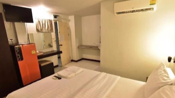 A hotel room with a bed, a desk, a mirror, and an air conditioning unit. - CK Residence (Pattaya)