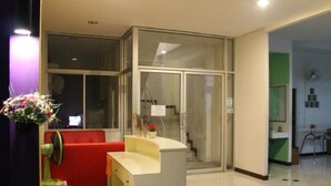 A hotel lobby with a reception desk, a red seating area, a staircase, and a green wall. - CK Residence (Pattaya)