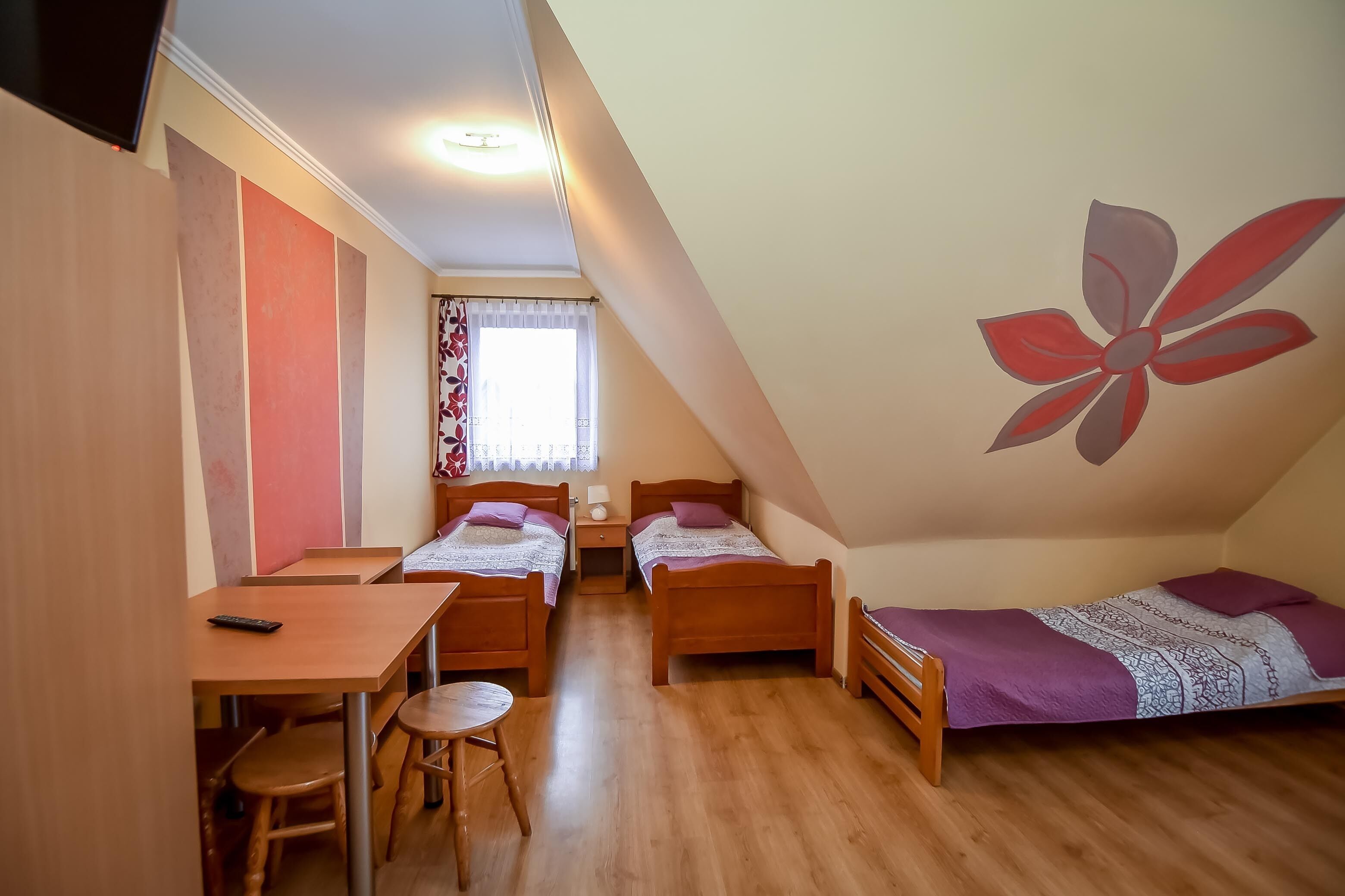 A dormitory room with two single beds, a desk, and a chair.