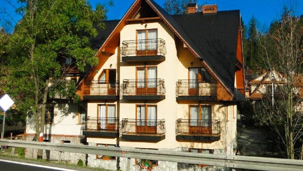Un immeuble à plusieurs étages, doté de balcons, d’un toit en pente et d’une base en pierre.