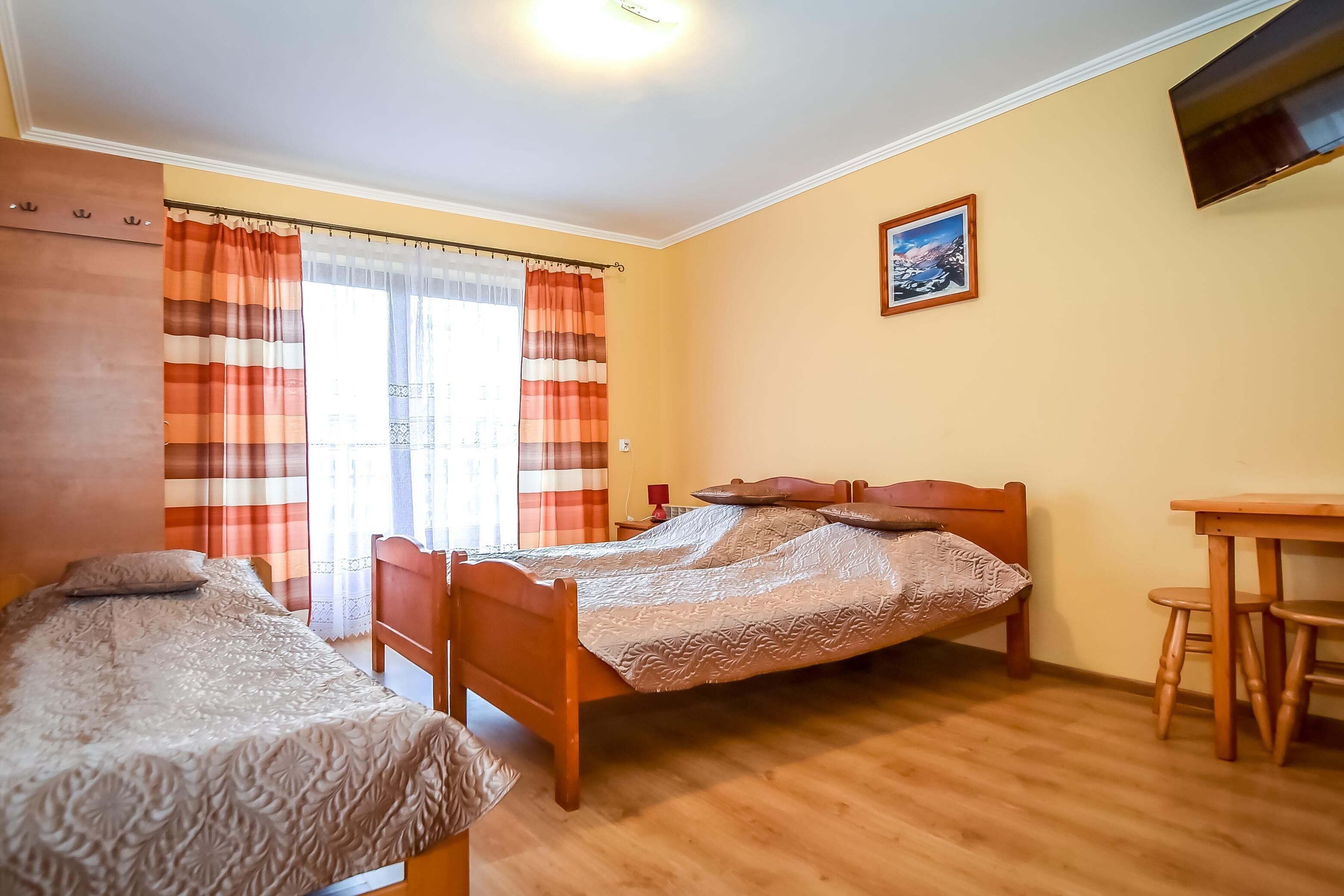 Quarto com duas camas, uma escrivaninha de madeira e uma cadeira.