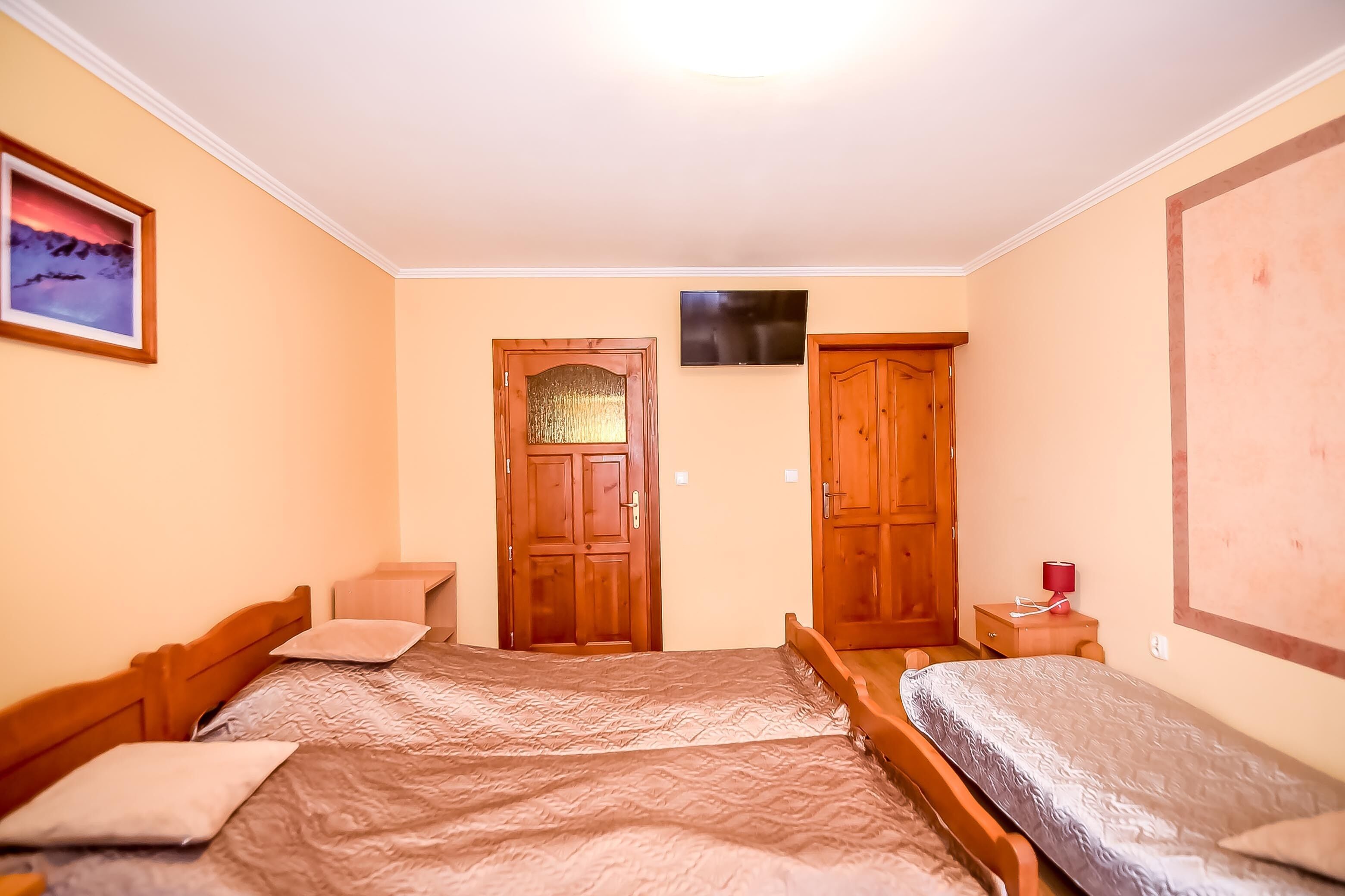 Un dormitorio con dos camas, un armario de madera, un televisor y un cuadro en la pared.