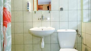 Un bany amb un lavabo blanc, un vàter i un mirall sobre el lavabo.