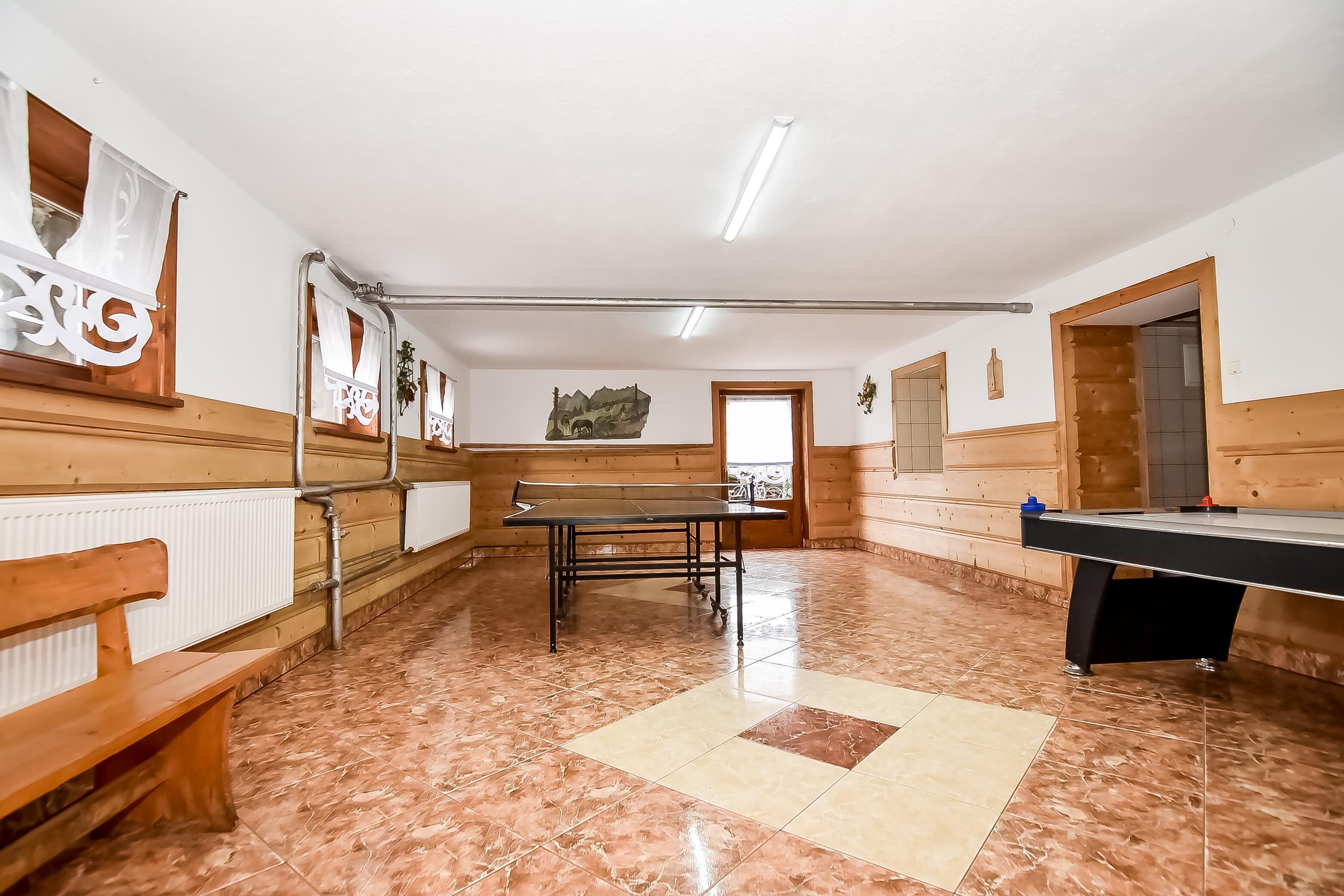 Una habitación con mesa de billar, bancos de madera y un mural en la pared.