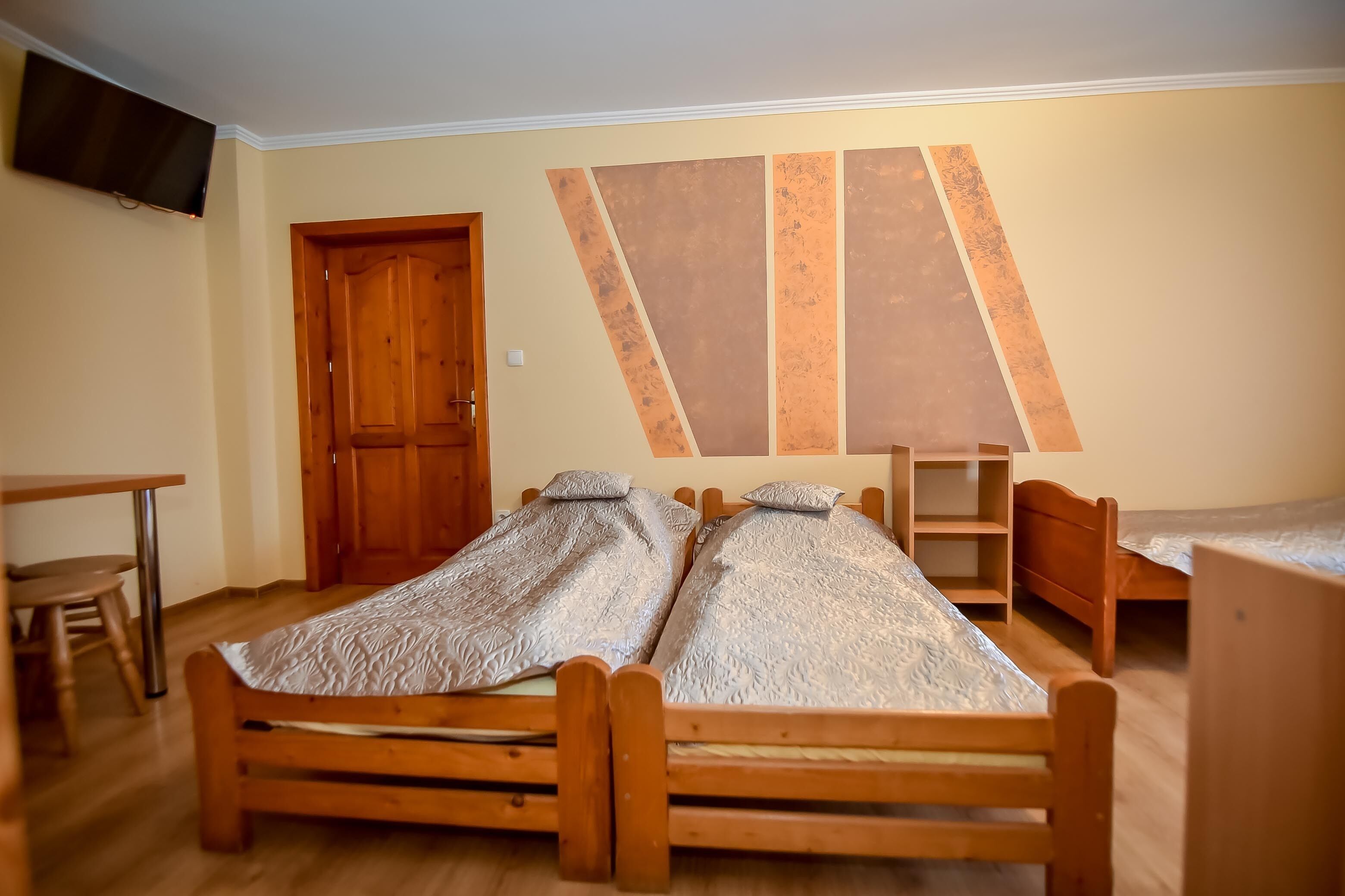 A room with two wooden beds, a wooden desk, and a chair.