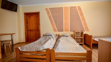 A room with two wooden beds, a wooden desk, and a chair.