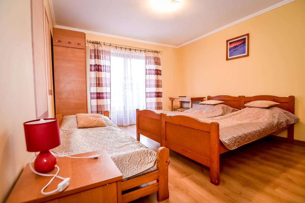 Un dormitorio con dos camas de madera, un escritorio con una lámpara roja y un armario.