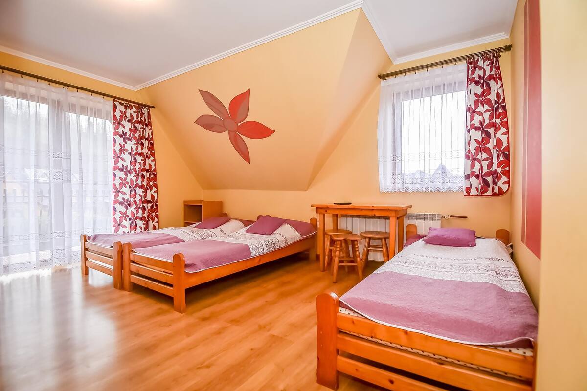 Una habitación con dos camas de madera, una mesita y una silla.