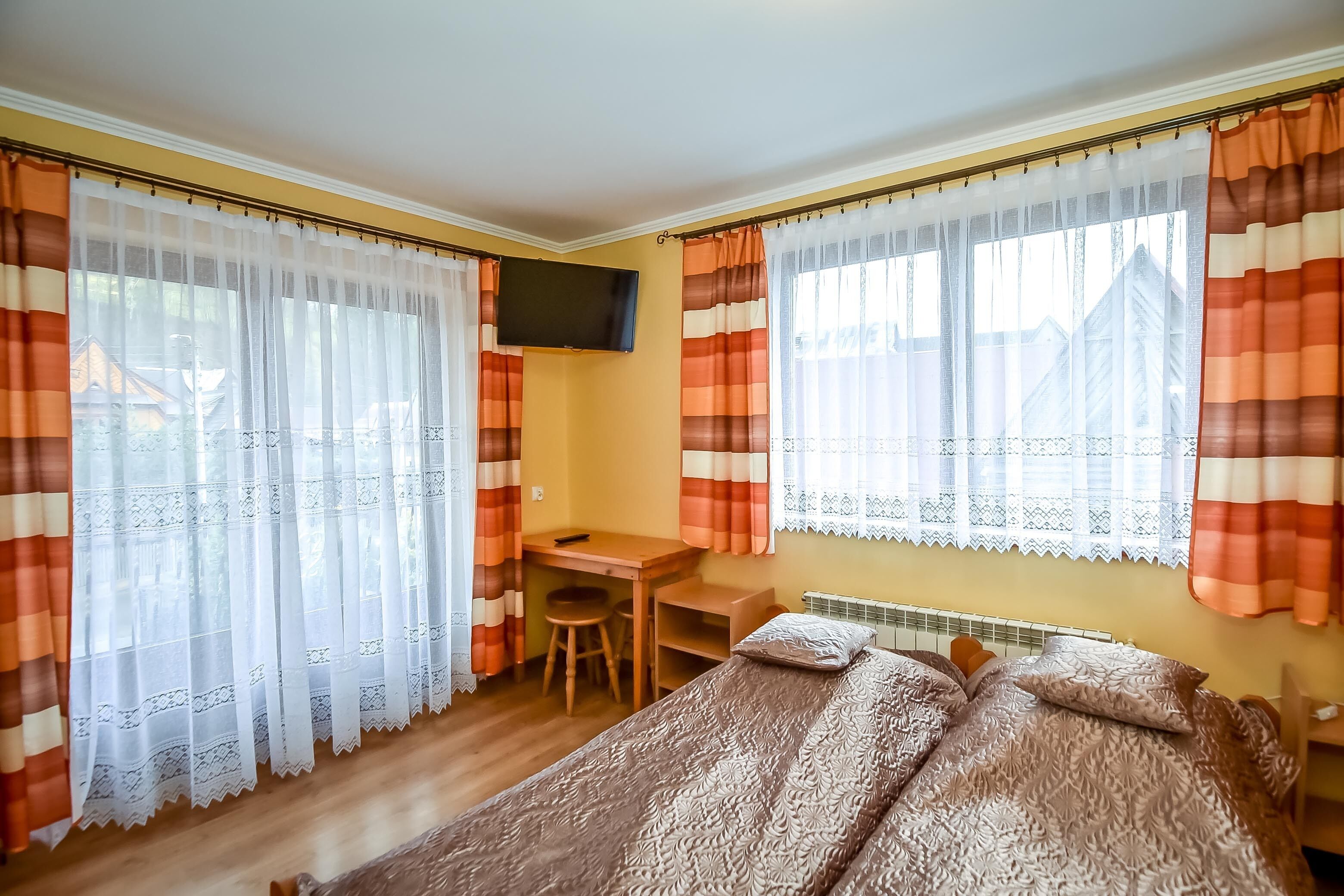 A bedroom with a bed, a desk, and a TV.