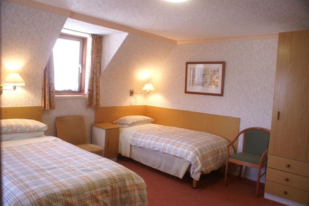 A room with two beds, a desk, a chair, and a wardrobe.