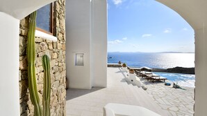 Una terraza con muro de piedra, un cactus y vista al mar.