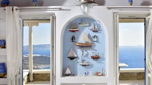 Habitación con vista al mar, decorada con una colección de barcos modelo en la pared y una mesa de comedor con sillas.
