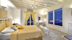 Un dormitorio con una cama grande, un tocador y vistas de un paisaje urbano nocturno.