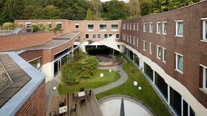 Une cour avec un bâtiment en briques, un espace de repos abrité et un petit jardin.