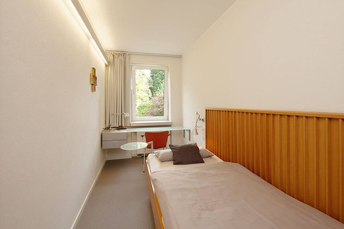Una habitación de hotel pequeña con una cama, un escritorio y una ventana.