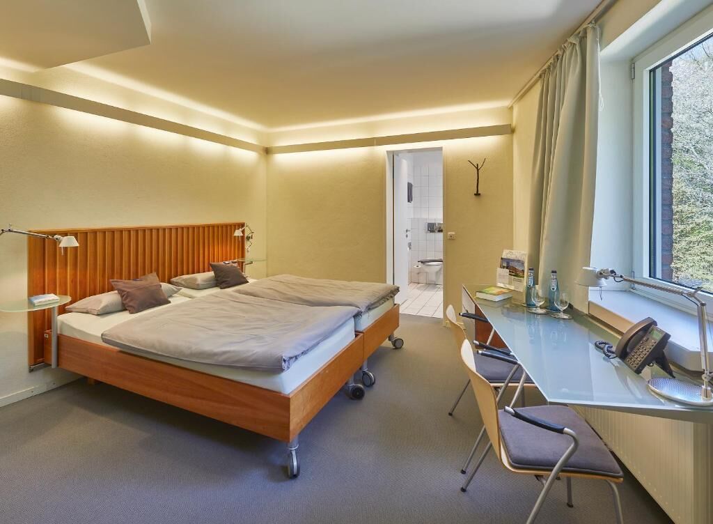 Une chambre d’hôtel avec un lit double, des tables de chevet, un bureau avec une chaise et une fenêtre.