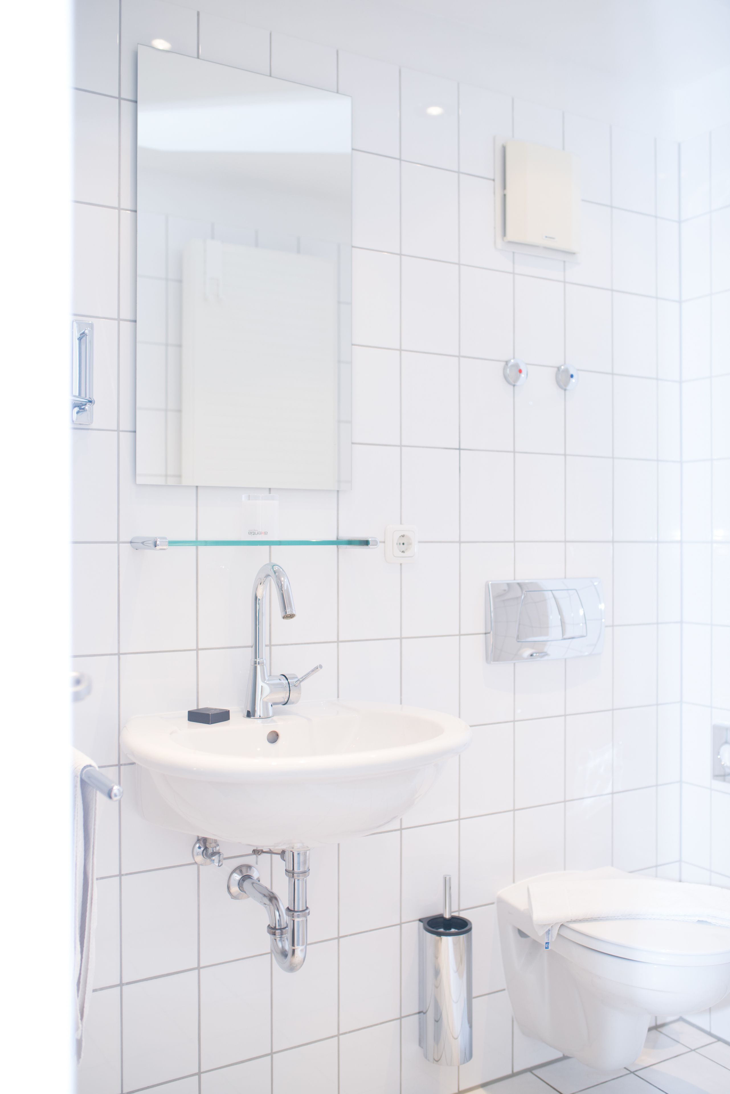 Ein modernes Badezimmer mit Waschbecken, Spiegel und Toilette in Weiß.