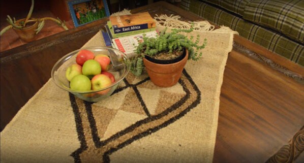 Une table sur laquelle se trouvent un bol de pommes, une plante en pot et un livre intitulé « Afrique de l’Est ».
