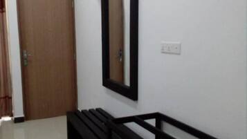 A hallway with a wooden door, a bench, a wall-mounted mirror, and a ceiling fan.