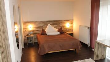 Un dormitorio con cama, mesitas de noche, radiador y espejo.