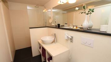 Un baño moderno con lavamanos blanco, espejo y ducha.