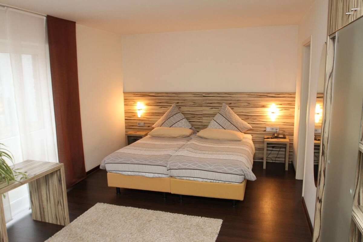 A modern bedroom with a large bed, bedside lamps, and a wooden headboard.