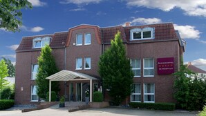 A hotel with a brick facade, multiple windows, and a covered entrance. - Designhotel Im Südfeld (Kamen)