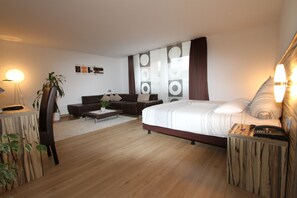 A modern bedroom with a large bed, a sofa, a coffee table, and a desk with a lamp. - Designhotel Im Südfeld (Kamen)