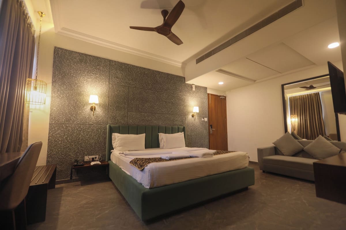 Una habitación de hotel moderna con una cama grande, un sofá, un escritorio y un ventilador de techo.