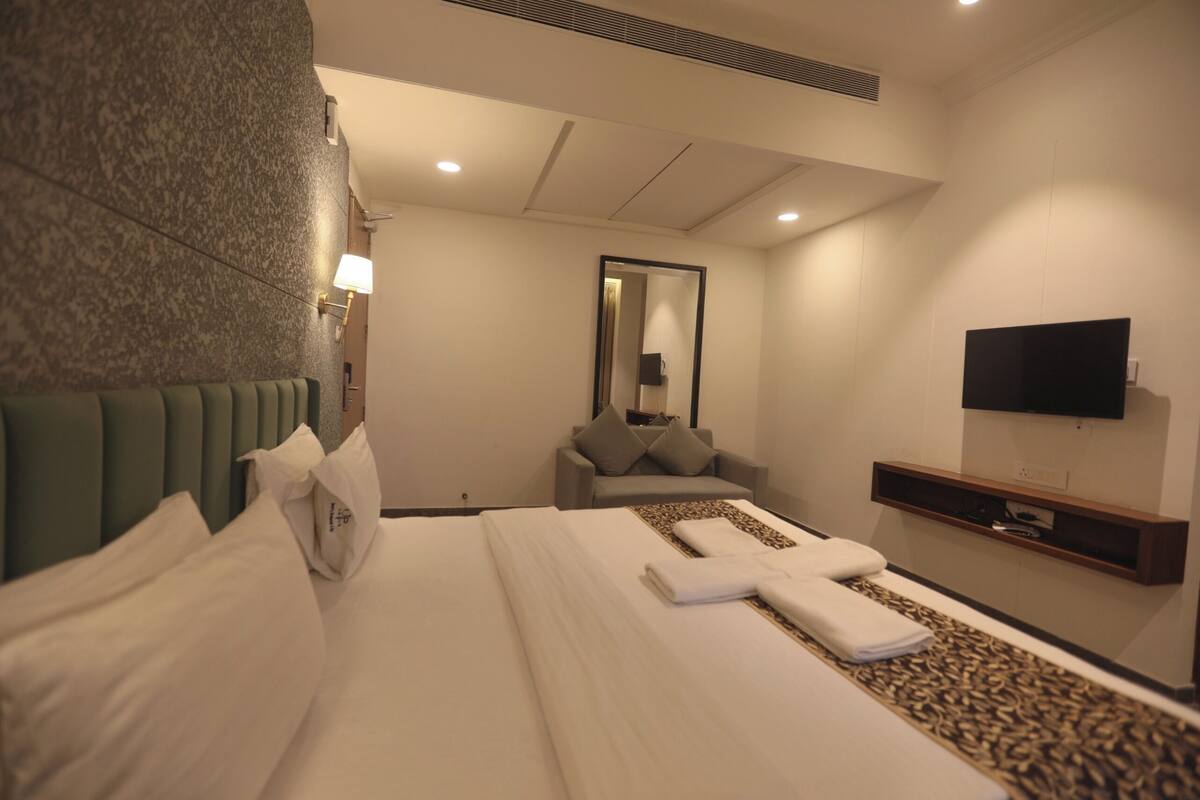 Una habitación de hotel con cama, sofá, televisor y espejo.