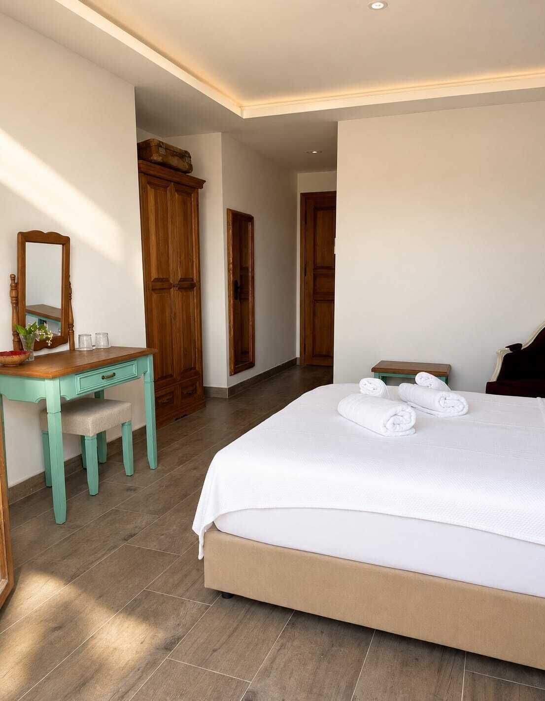 A bedroom with a bed, a desk, and a mirror.