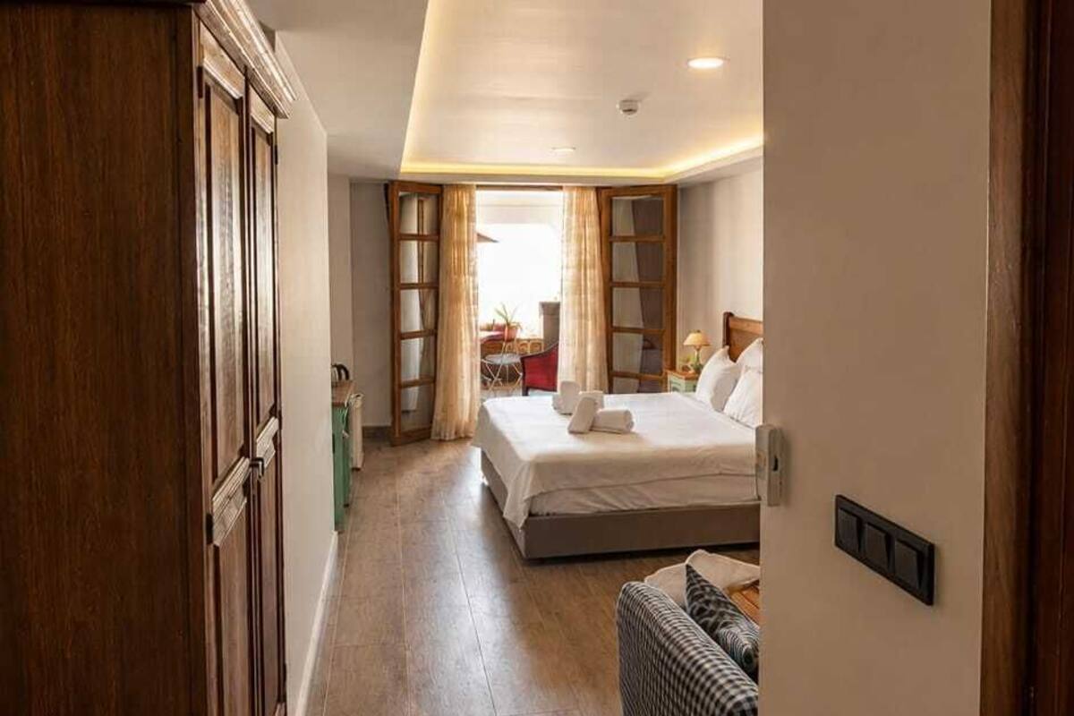 Quarto de hotel com cama, um espaço de estar pequeno e um guarda-roupa de madeira.
