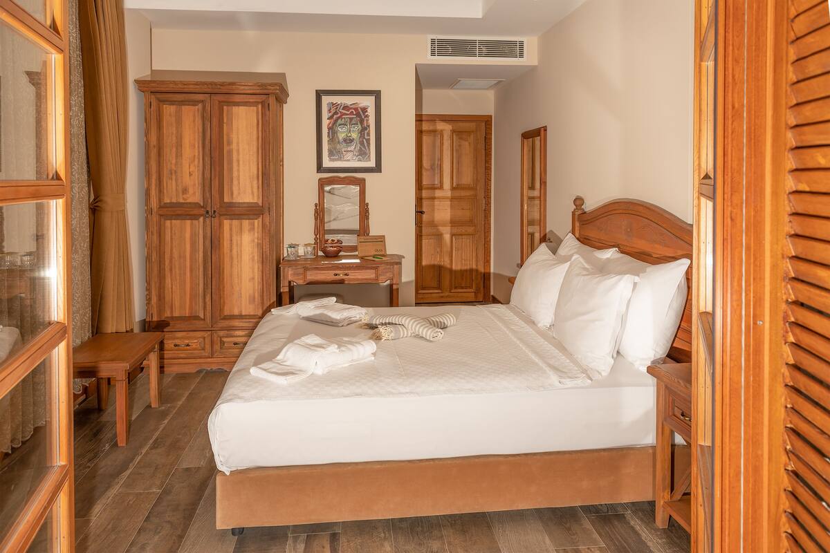 Um quarto com cama, cômoda, mesa de cabeceira e guarda-roupa de madeira.