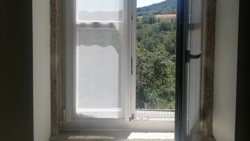 Una habitación con un ventanal, vistas a un paisaje verde y una puerta blanca.