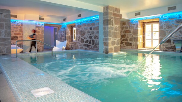 Una piscina interior con paredes de piedra y superficie de agua cristalina.