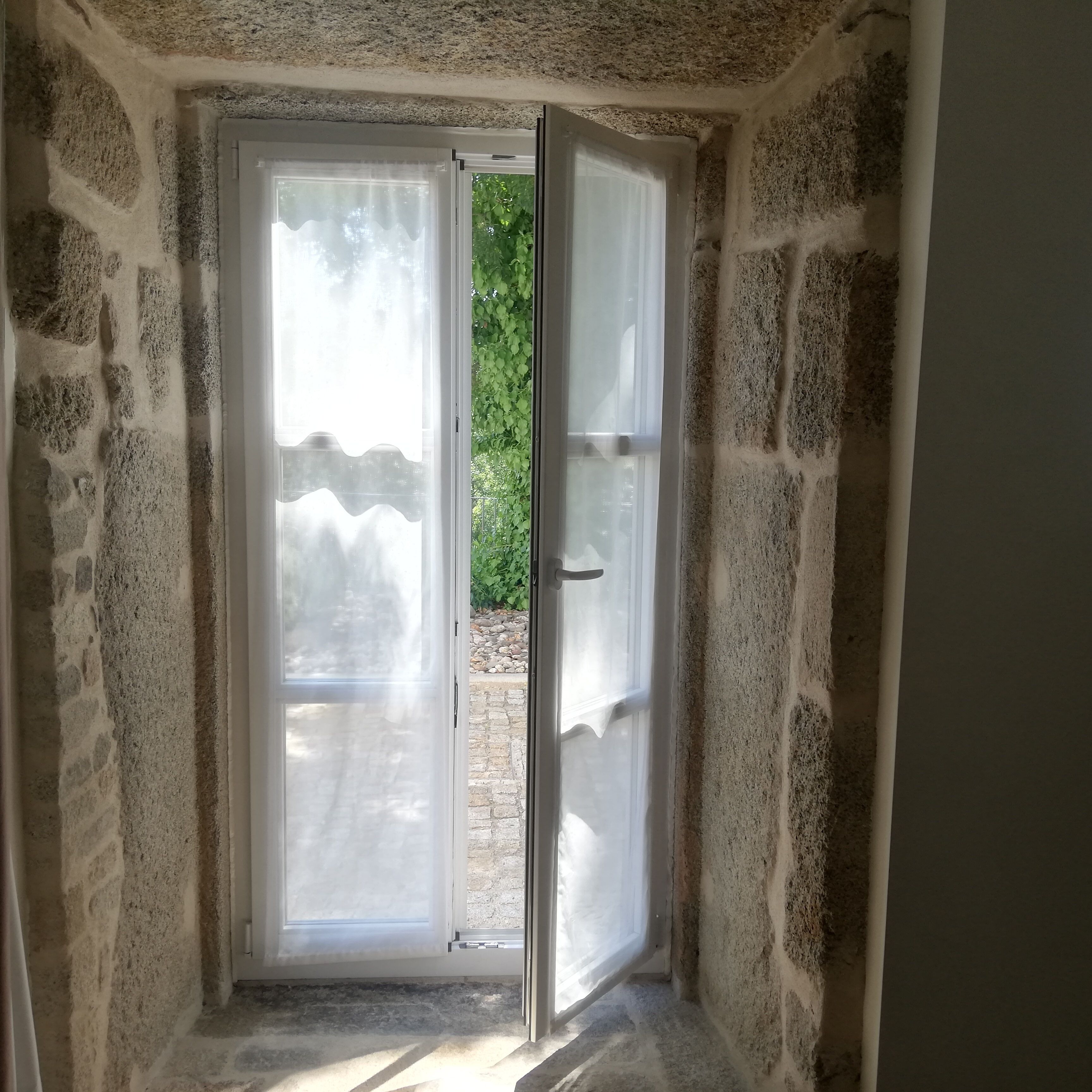 A stone-walled room with a sliding glass door leading to an outdoor area.