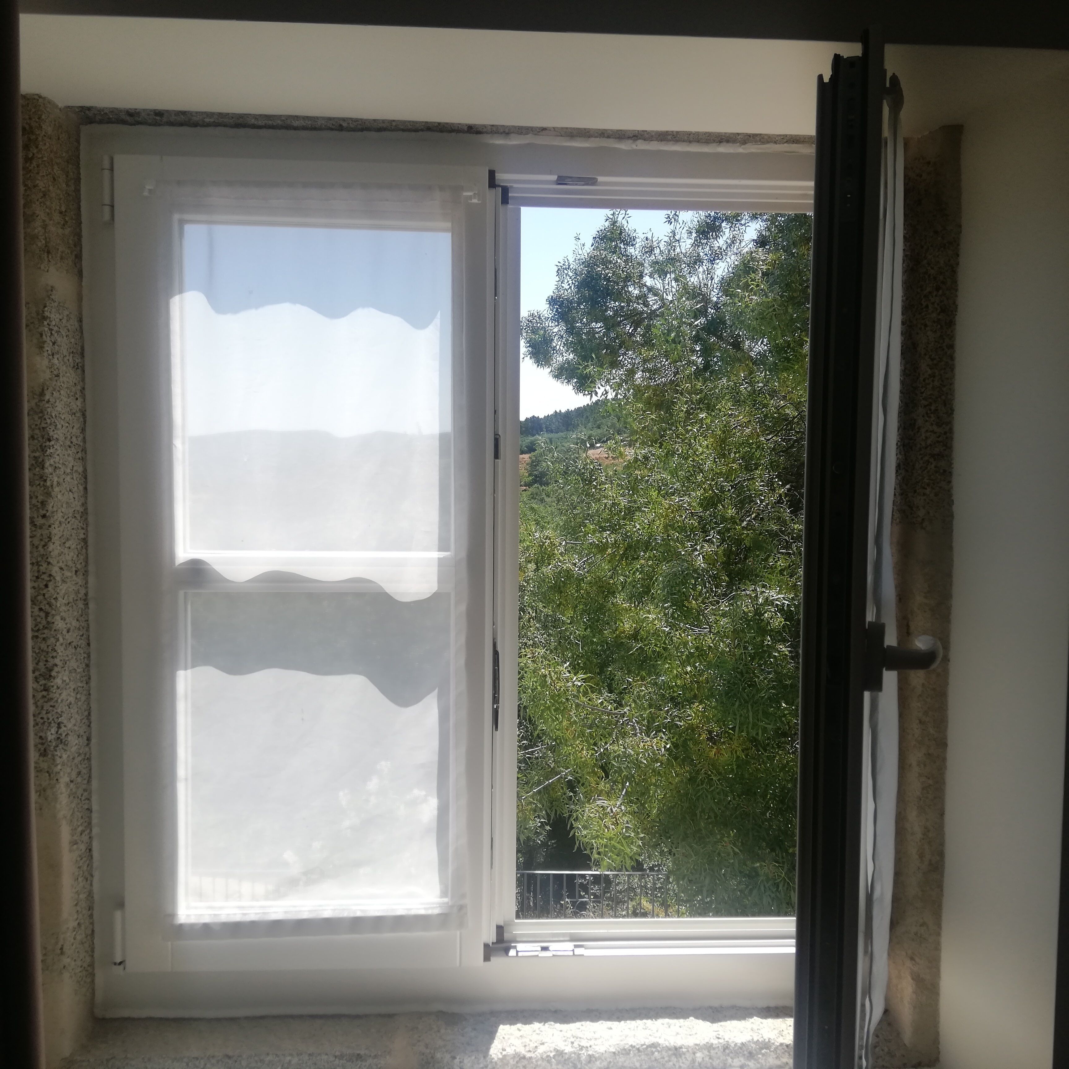 A window with a view of trees and hills outside.