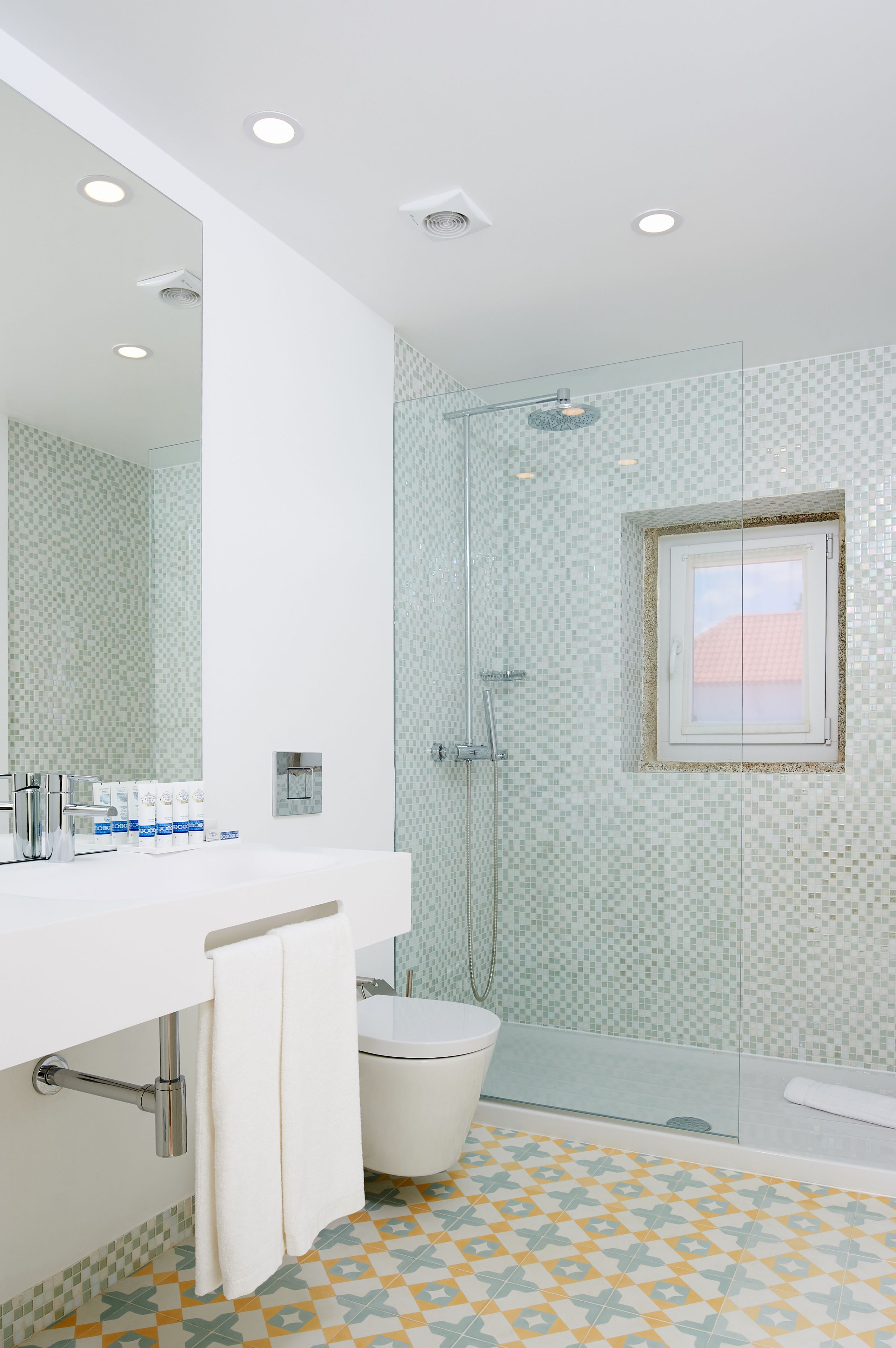 A bathroom with a white sink, a glass shower enclosure, and a patterned floor.