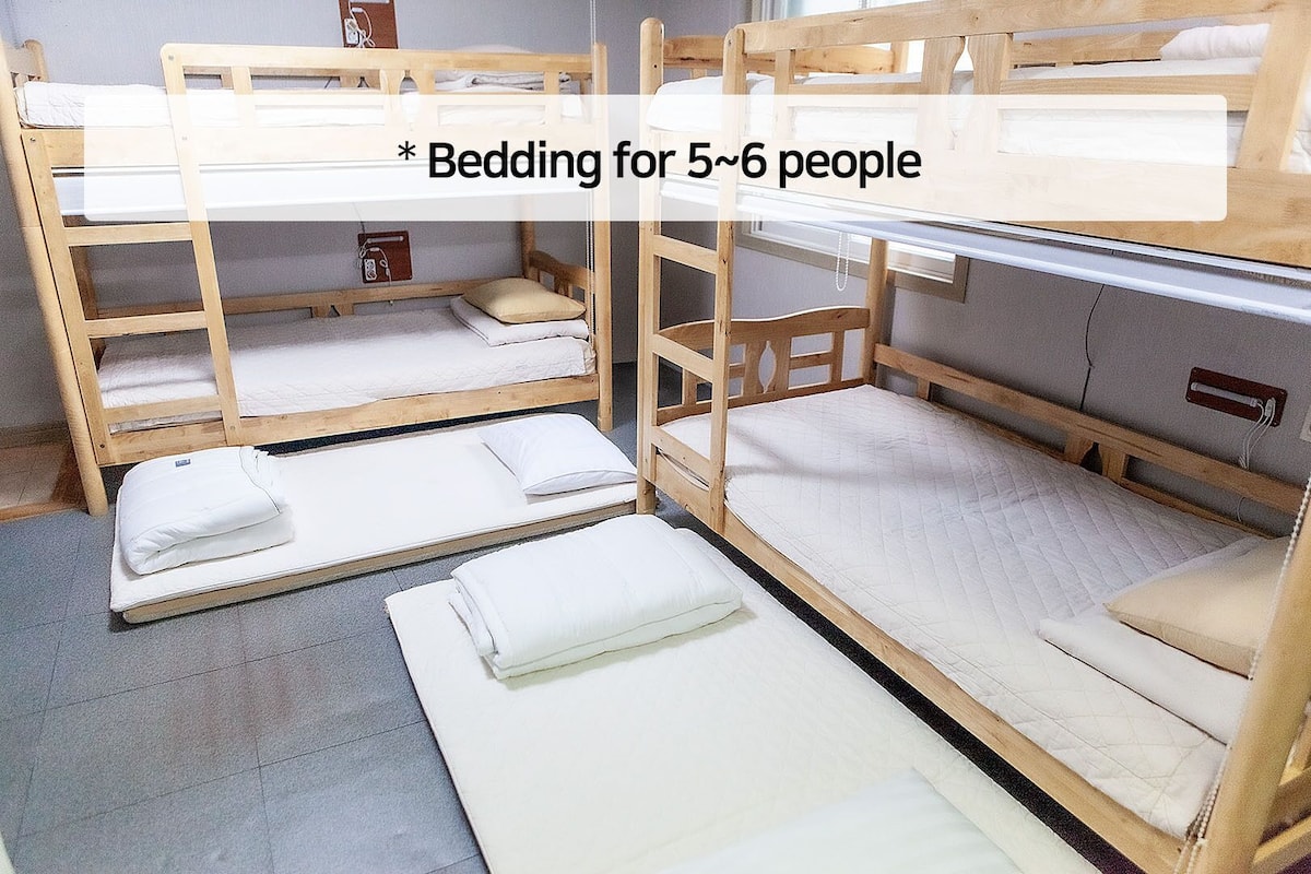 Une chambre avec des lits superposés, comprenant deux lits inférieurs et un lit supérieur, conçue pour accueillir de 5 à 6 personnes.
