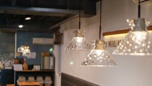 A restaurant interior with hanging pendant lights, wooden tables, and a cushioned bench along the wall. - MIHOJAE Hostel Busan (Busan)