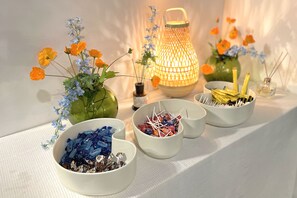 A table with decorative items including vases with flowers, a lantern, and bowls of candies. - MIHOJAE Hostel Busan (Busan)