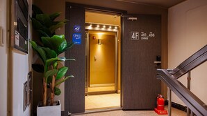 A hotel entrance with a plant, a sign for room 401-406 lounge, and an emergency exit sign. - MIHOJAE Hostel Busan (Busan)
