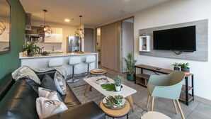 A modern living room with a sofa, coffee table, and a TV mounted on the wall.