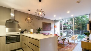 Una cocina moderna con una isla central, horno empotrado e iluminación colgante.