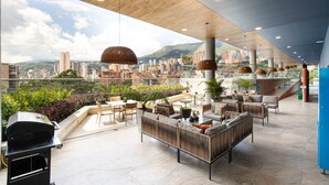 Un bar en la azotea con mesas al aire libre, una parrilla y vistas de la ciudad.