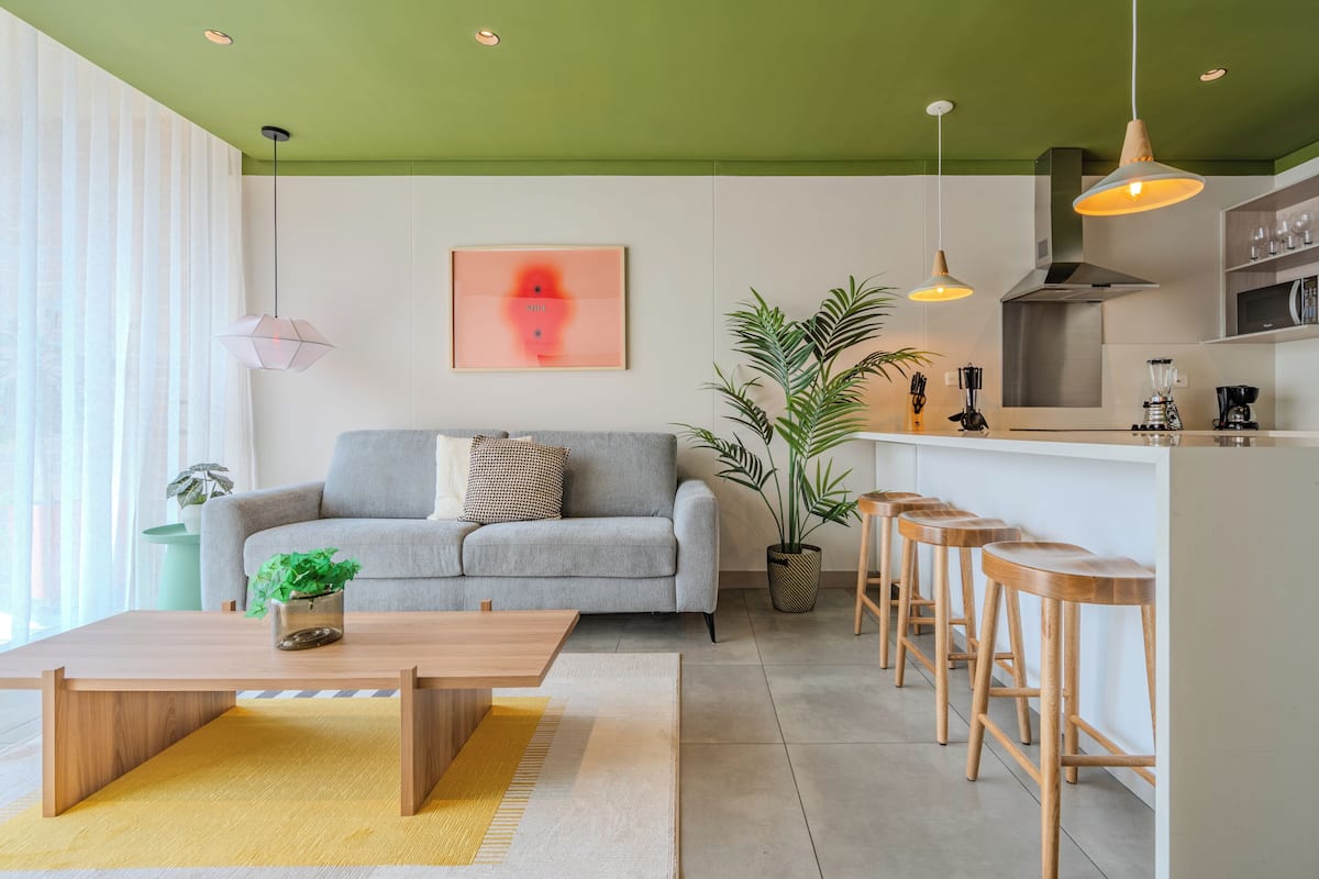 A modern living room with a sofa, coffee table, and bar stools.
