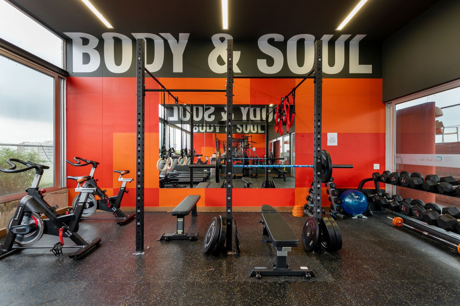 A gym with a mirrored wall, weightlifting equipment, and cardio machines.