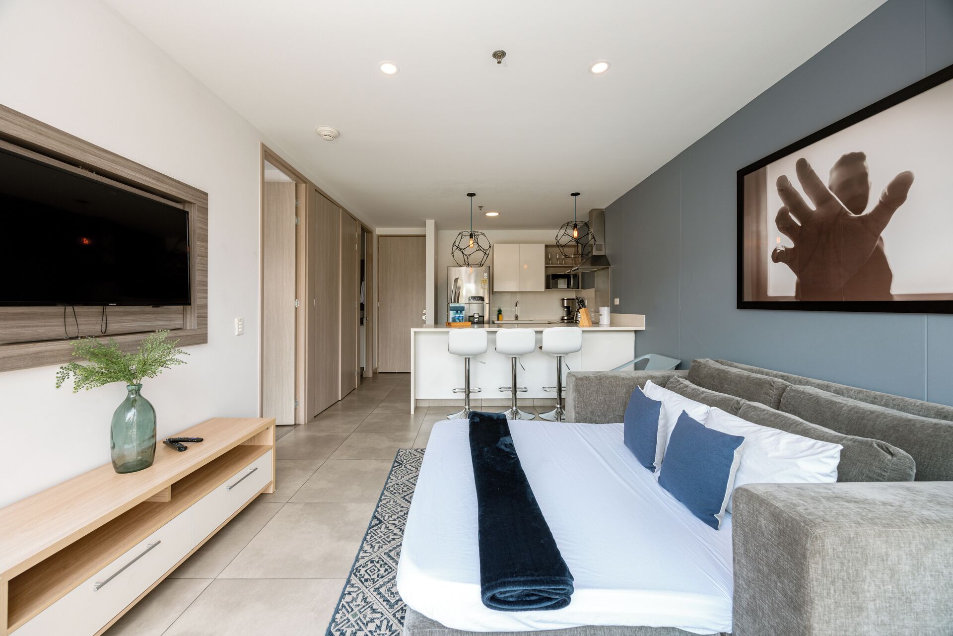 Een moderne woonkamer met een bank, een televisie, een keukenhoek en een eettafel.