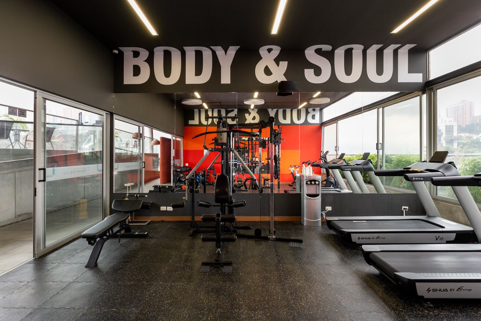 A gym with treadmills, weight machines, and a large mirror.